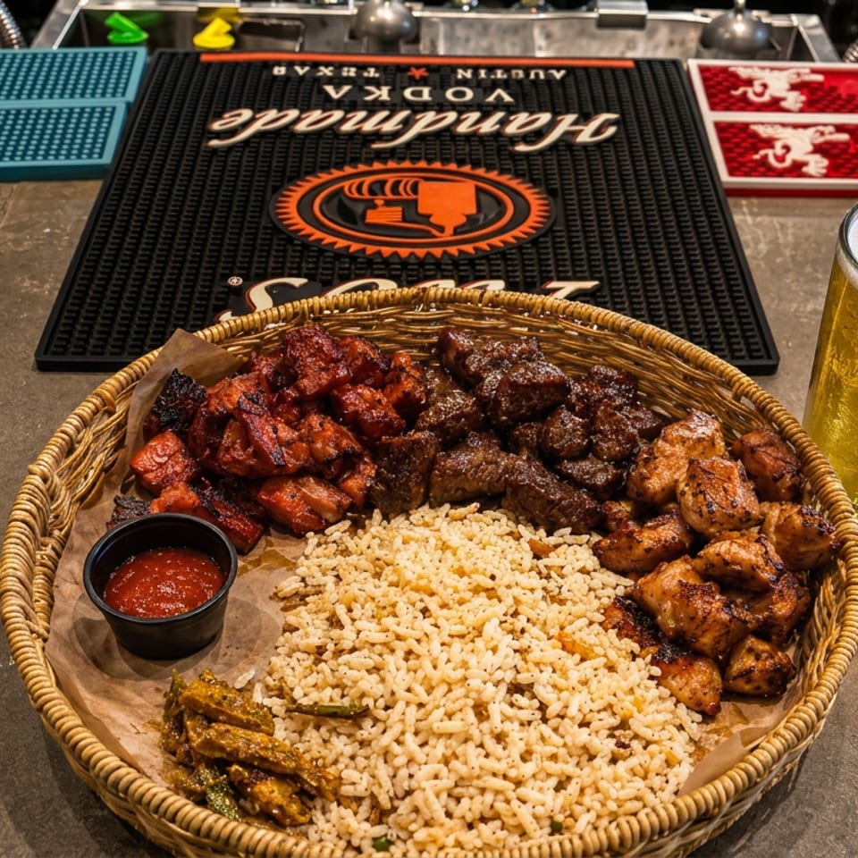Wicker platter of grilled meats, rice, peppers, and dipping sauce beside a frothy beer on a restaurant bar.